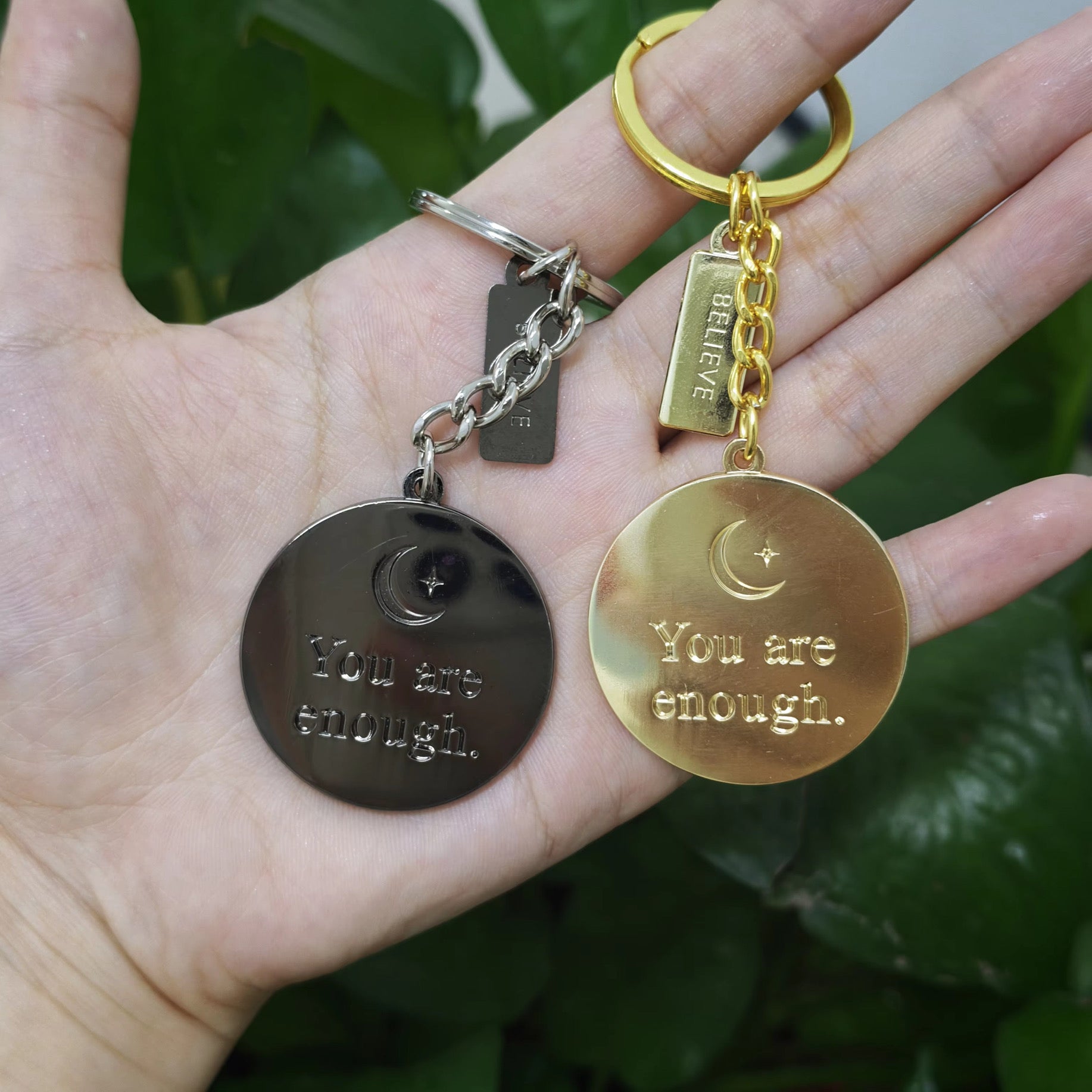 Real life Gold and Charcoal keychains front view in hand